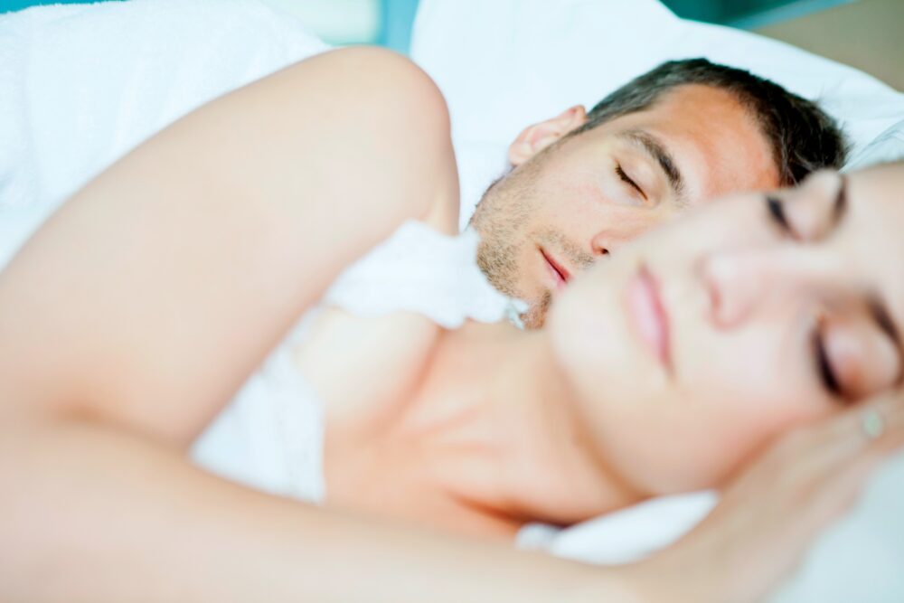 A couple sleeping together in a bed.