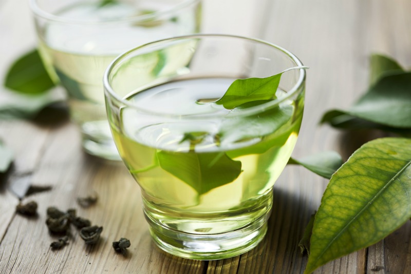 green tea leaves brewed in a clear glass.