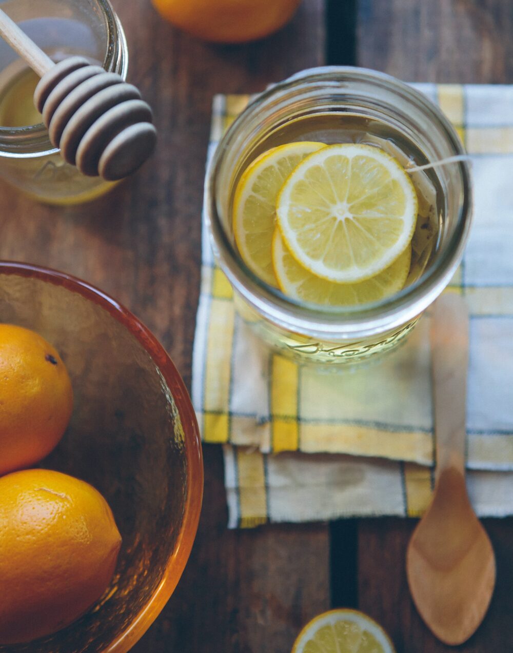 A cup of tea with lemons and honey, with the accompanying ingredients visible nearby.