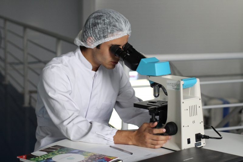 A man analysing a glass slide on a microscope.