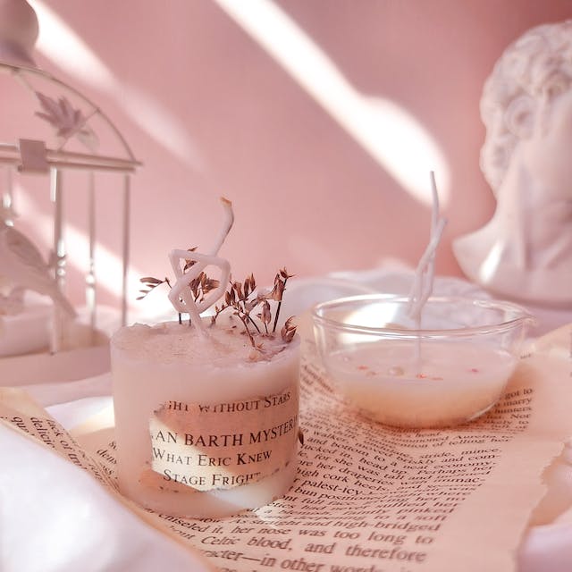 Two pink scented candles in a pastel pink room.