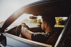 A man drives a car on the American side of the road.