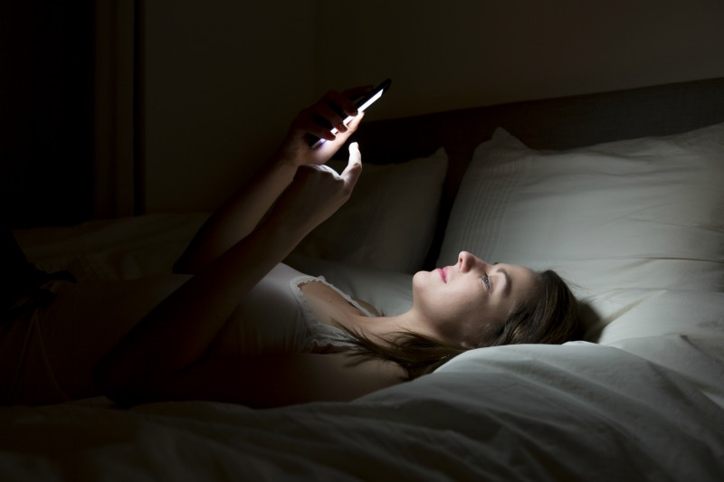 woman looking at phone whilst in bed